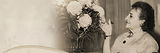 Sepia photo of a woman looking at a large flower bouquet.