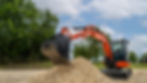 Orange excavator digging into gravel pile