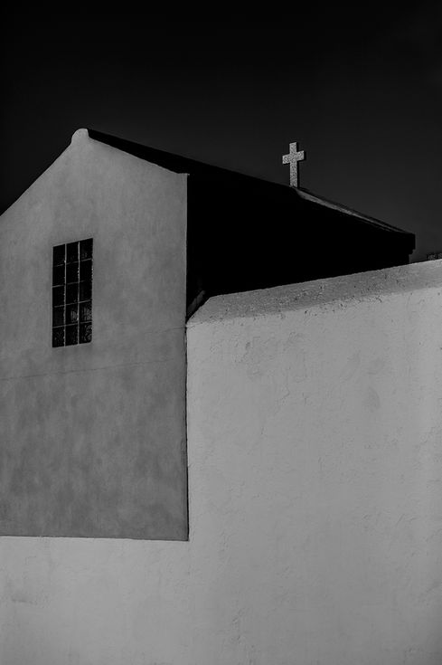 Chapelle en noir et blanc avec croix sur le toit.