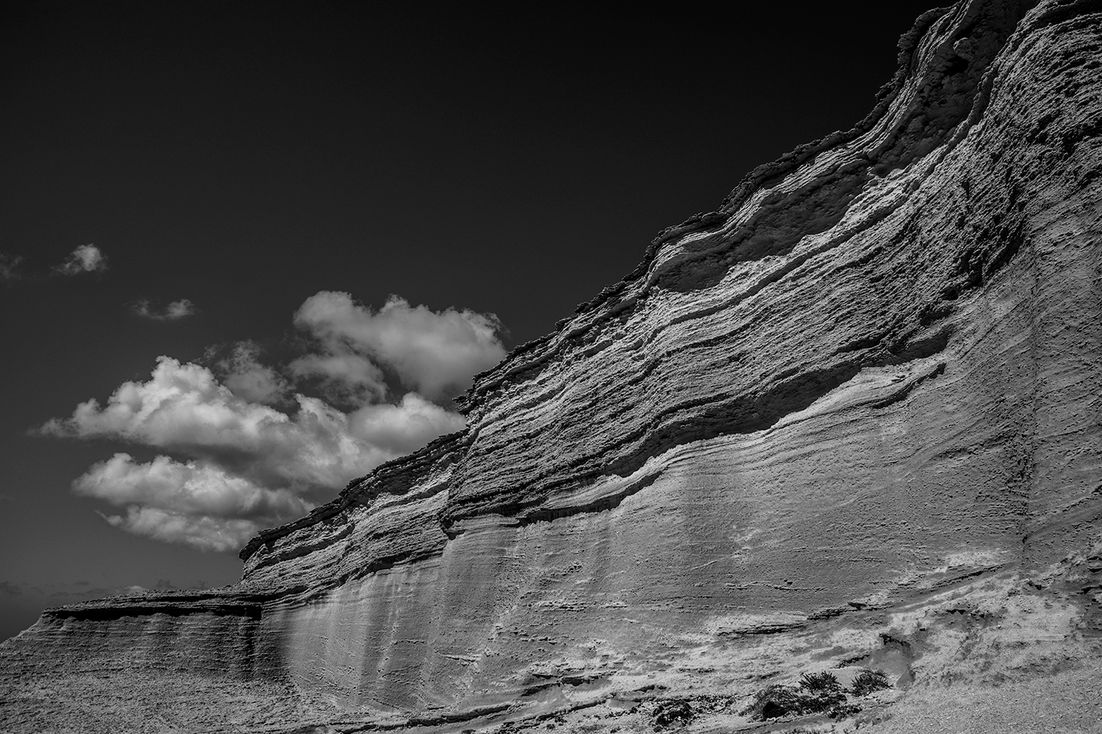 Rochers stratifiés en noir et blanc sous un ciel nuageux