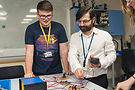A JLC teacher looks at an electrical experiment they have set up with a student