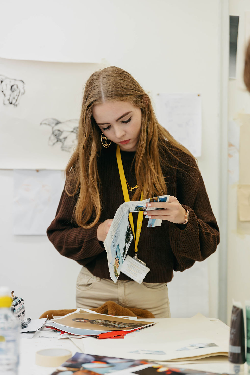 A JLC student cuts out images from a magazine with scissors