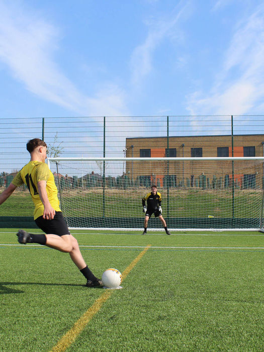 A John Leggott College student kicking a ball into a net on the 3G pitch