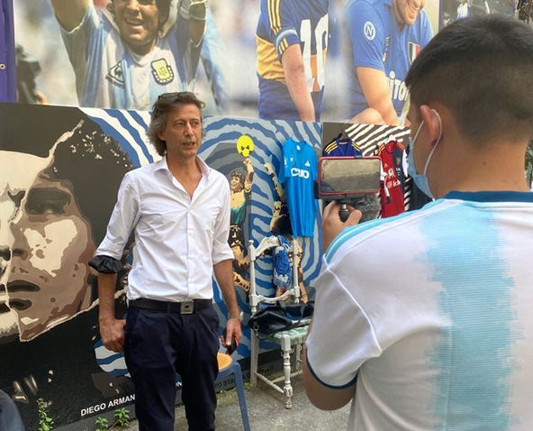 Uomo intervistato davanti a un murales di Diego Armando Maradona