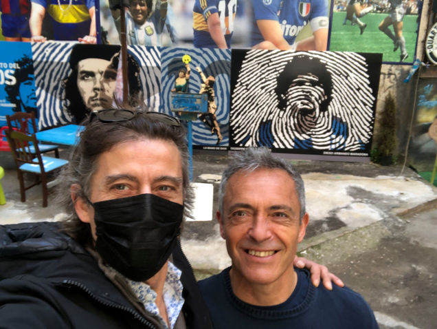 Due uomini davanti a murales di Maradona e Che Guevara