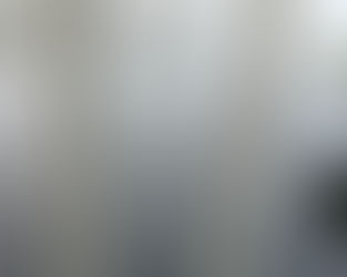 Spindelväv täckt med daggdroppar spänner över ett metallräcke, fångar morgonens ljus.