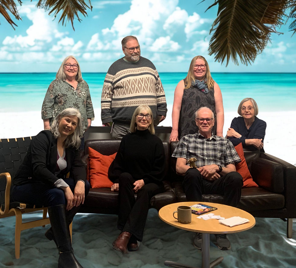 A group of people sitting and standing around a sofa and chair with an AI generated beach background representing the up-and-coming holiday season.
