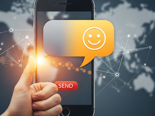 A mobile phone with a prominent send button on top of a map of the world in the background, a network of connected dots representing a message being transported. There is a hand in a "thumbs up" gesture and a smiley message indicated coming out from the telephone.