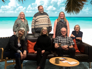 A group of people sitting and standing around a sofa and chair with an AI generated beach background representing the up-and-coming holiday season.