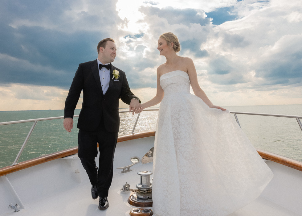 Newlyweds walking on the Gemini yacht at Catawba Island Club with beautiful skies behind them.