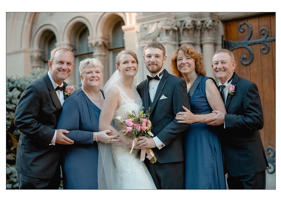 group shot of bride and grooms families together against a stone chapel