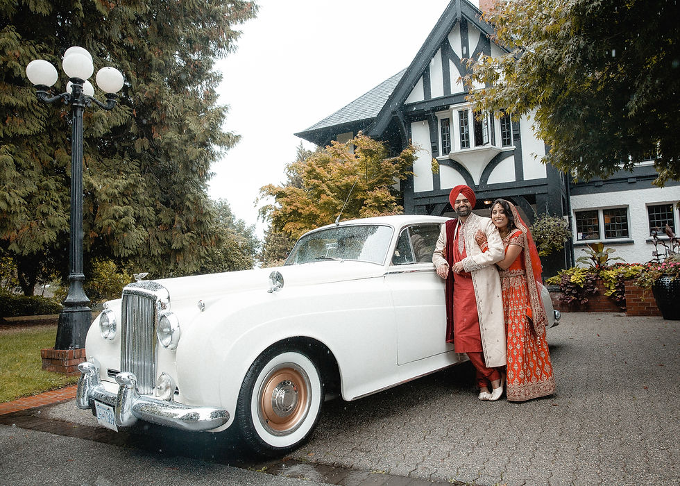 man and woman stand on the side of a rolls Royce she puts her arm around him.