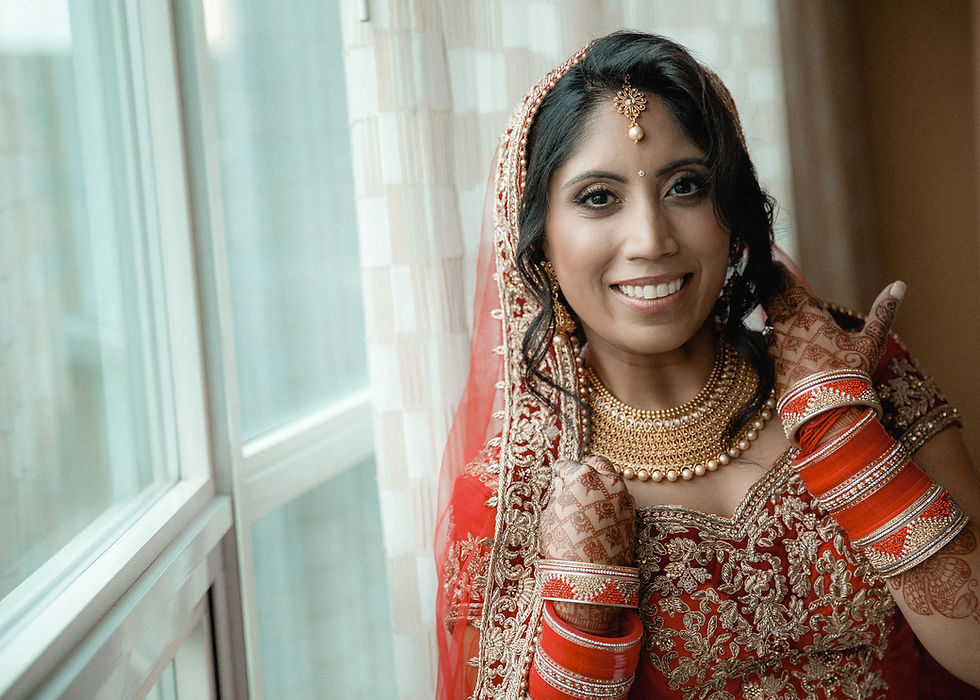 close up portrait of bride fully dressed in Indian outfit by windows of hotel room
