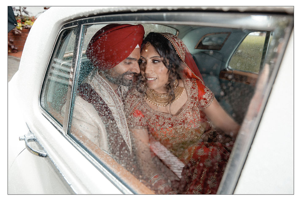 husband and wife sit in the back seat of a car looking towards each other