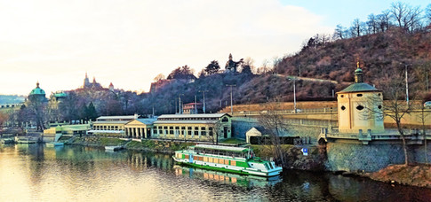 Pohled z Čechova mostu na kapli svaté Máří Magdalény, Občanskou plovárnu a Hanavský pavilon na vrchu Letné