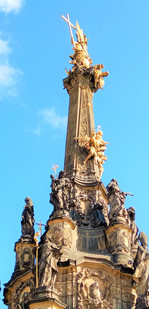Pozlacená dělová koule zasazená do dříku Sloupu Nejsvětější Trojice těsně pod vrchním sousoším je připomínkou ostřelování sloupu pruským vojskem