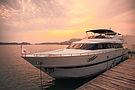 Luxury yacht docked at a wooden pier at sunset