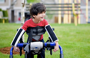 child walking in field with a gait trainer supporting his legs to walk