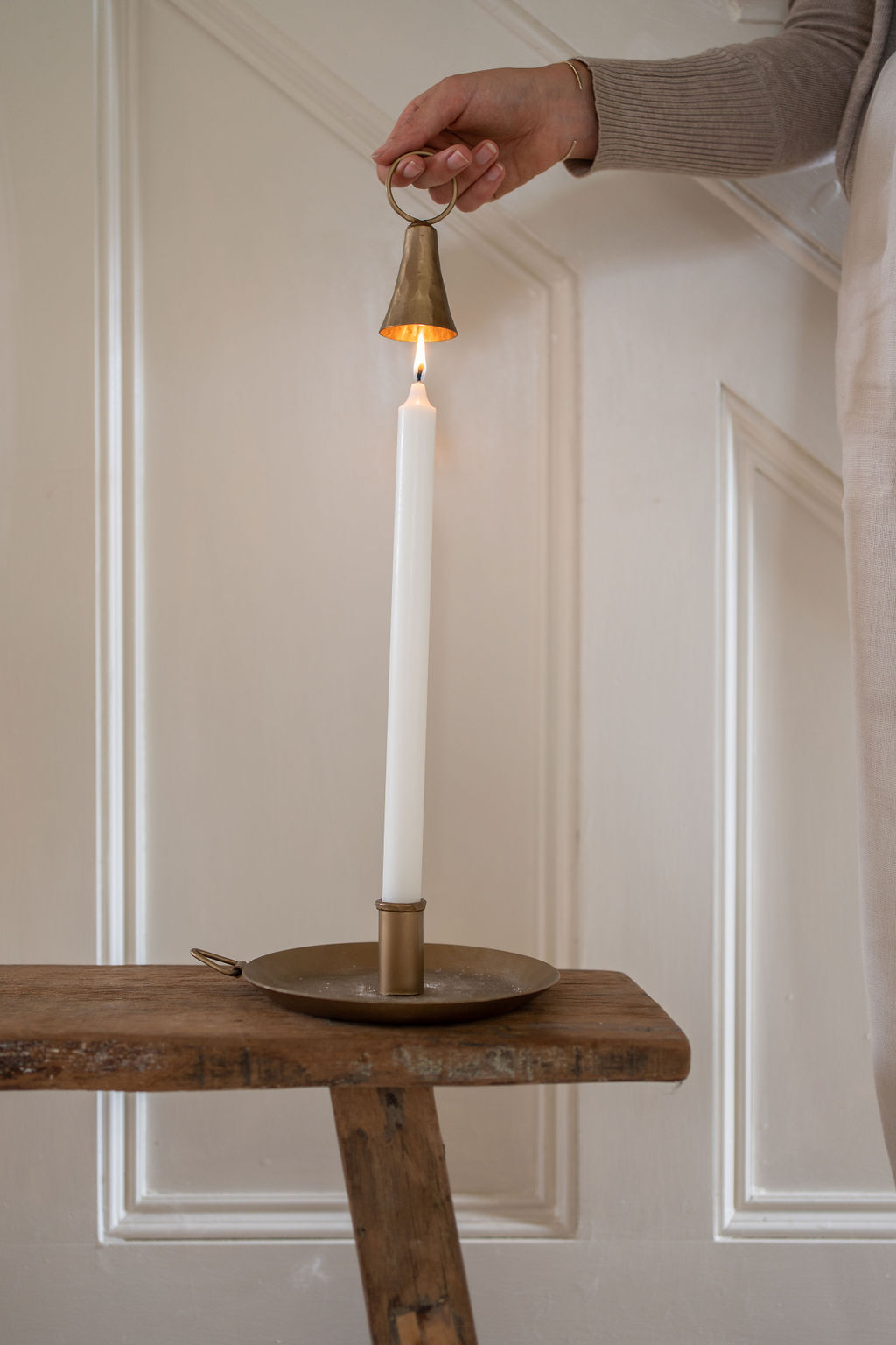 Bell-shaped brass candle snuffer designed for candle care, presented in a cotton drawstring bag with classic, elegant finish