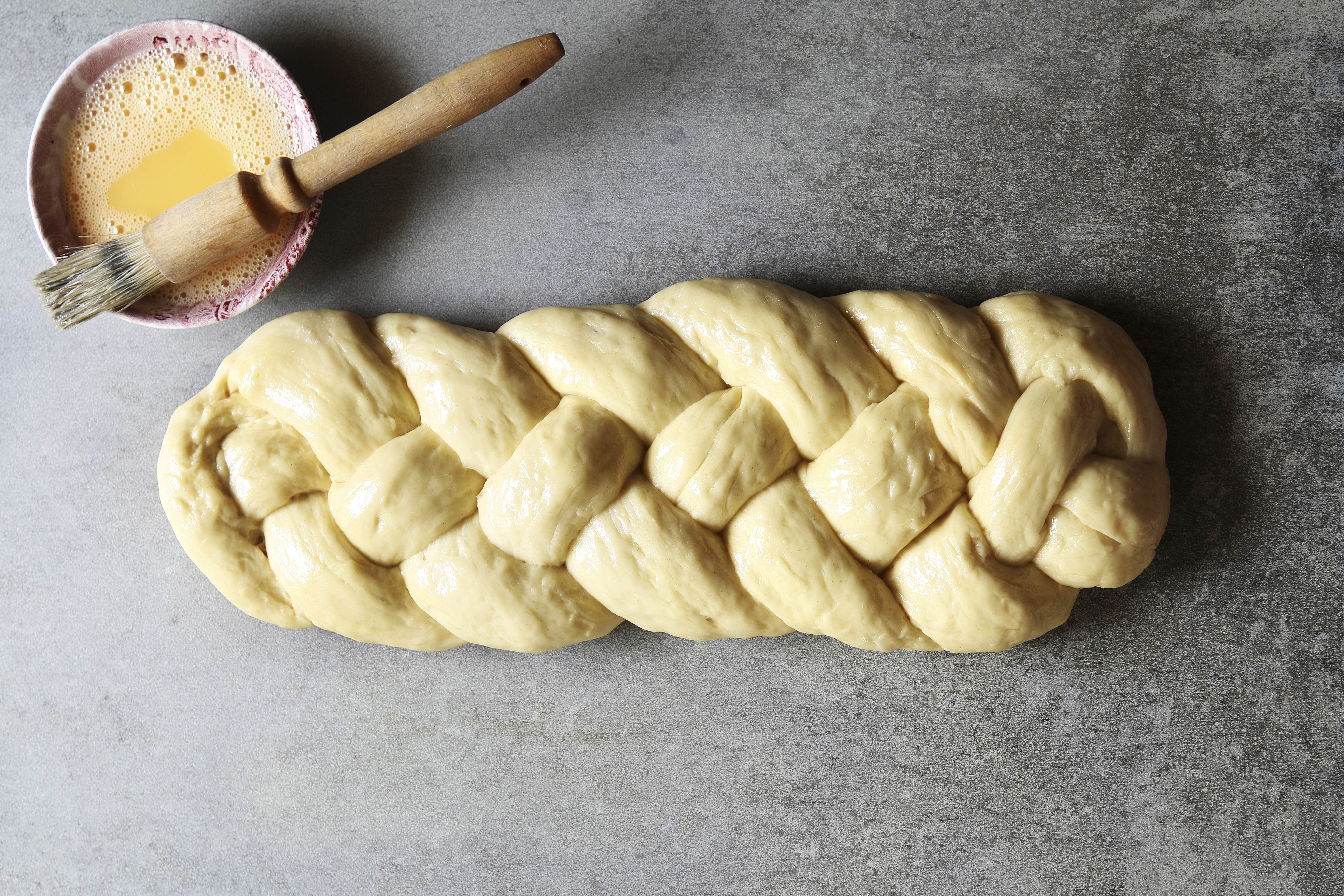 Preparing a challah for baking with an egg wash