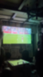 A large projector screen with soccer on in a dark room