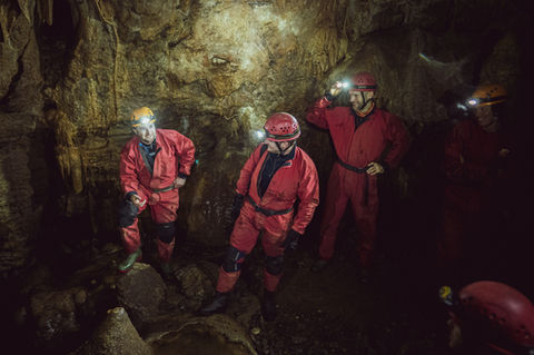 Caving instructor trainees moving through an underground passage on a UK training course