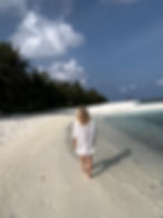 Woman walking on a white sanded beach in the maldives