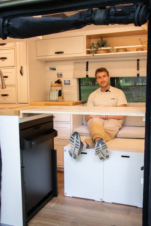 Man sitting inside custom Ram ProMaster camper van.