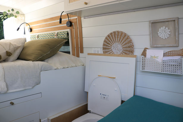 Camper van side wall with built-in storage and wicker decor.