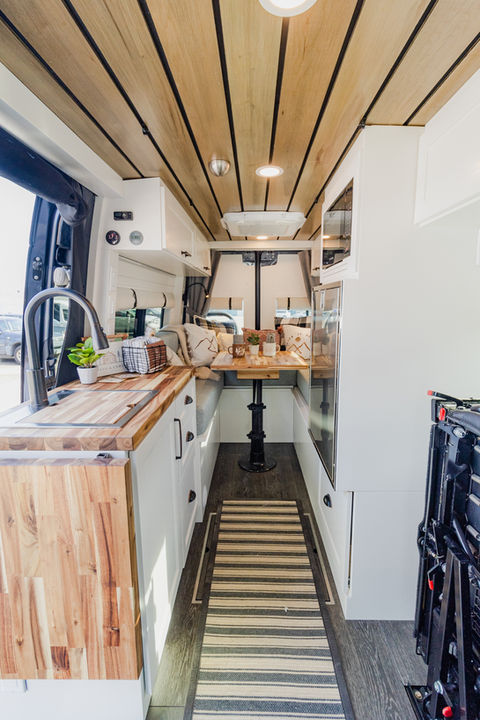 Camper van interior with wood ceiling and white cabinetry.