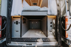 Under-bed garage storage area in a Drifter Vans custom campervan, showing organized compartments and premium finishes.