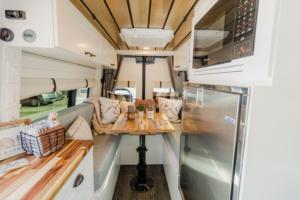 Camper van interior with dining table and bench seating.