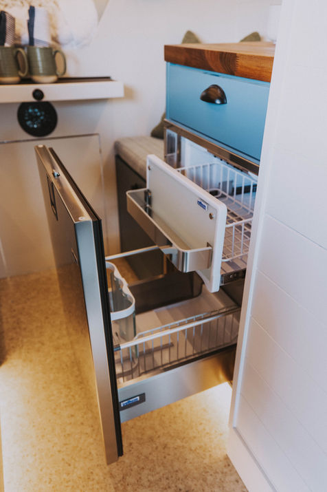 Camper van kitchen with pull-out drawers and hidden storage compartments.
