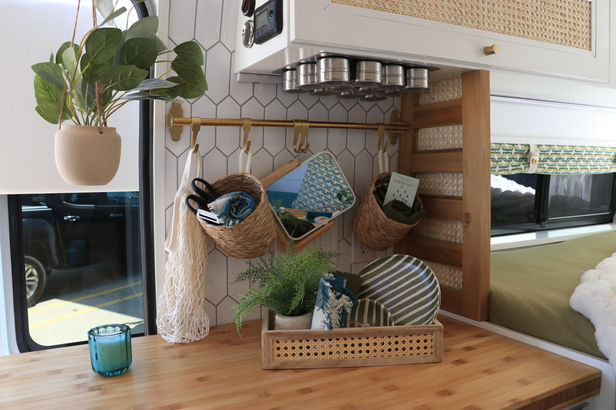 Camper van kitchen counter with hex tile backsplash and plants.