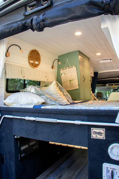 Camper van bed area with green and cream bedding.