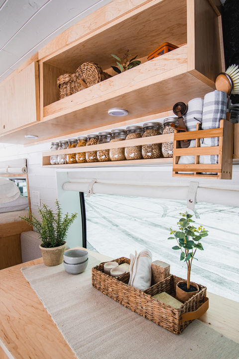 Wooden shelves and spice rack inside a minimalist camper van kitchen.
