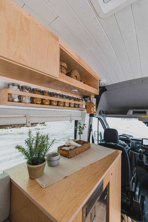 Camper van countertop with potted plant and light wood surface.
