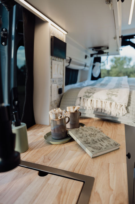 Camper van bed with patterned bedding and wooden details.