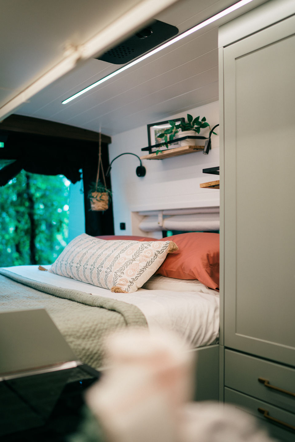 Camper van kitchen and bed area with light wood accents.