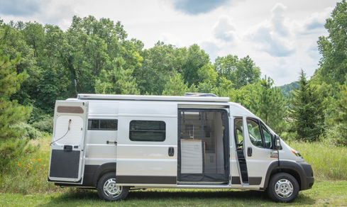 White Ram ProMaster camper van parked outdoors with side door open.
