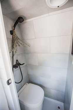 Camper van shower with white tiles and black shower head.
