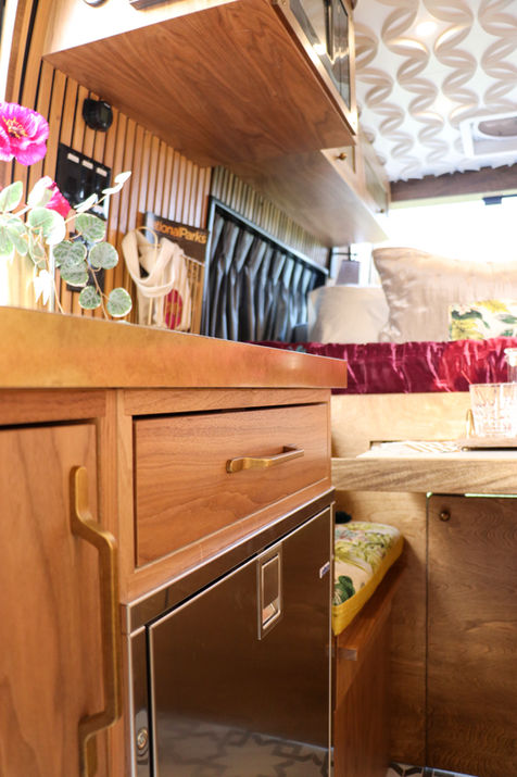 Camper van interior with wood drawers and built-in kitchen.