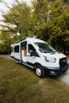 Ford Transit camper van with open door and wood interior.