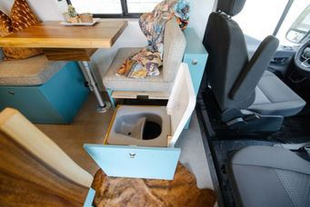 Camper van seat opened to reveal hidden storage compartment.