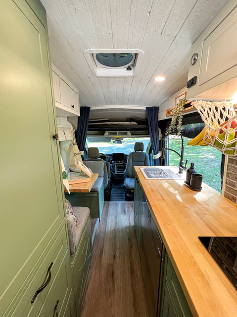 Camper van interior view showing kitchen and cab area.