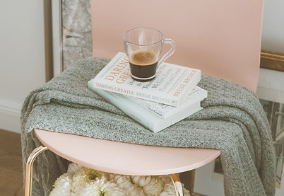 Cozy chair with a blanket, books, and a cup of coffee