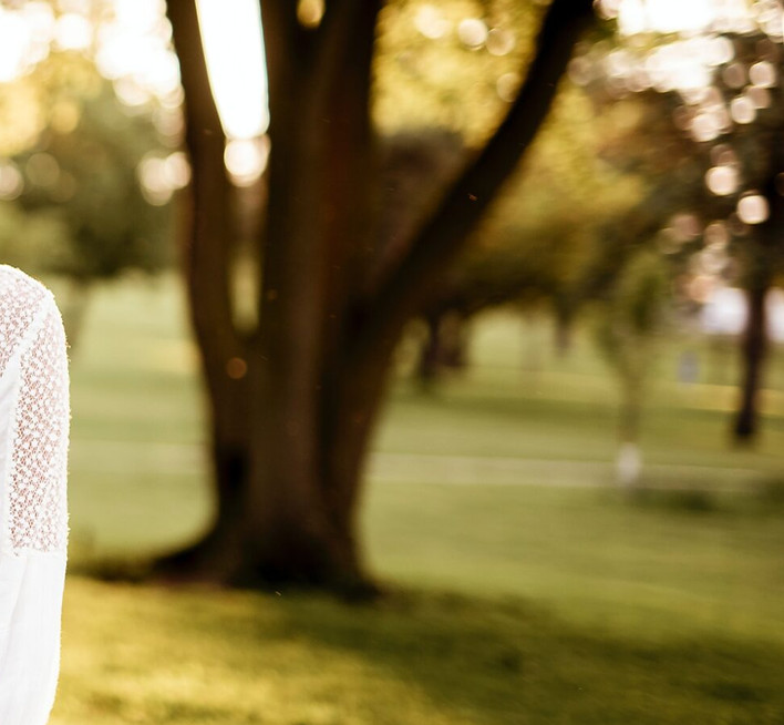 A smiling couple holding hands in a sunlit park.