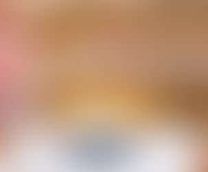 Armen van oudere vrouw en getatoeëerde persoon maken een vuistbump boven een taart op een blauwe taartstandaard. Vintage bank, gezellige sfeer.