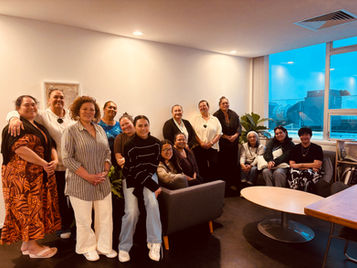 A group of Maori and Pacific women leaders gathered in a meeting room, smiling together after a governance wānanga. Some are standing and others are seated on couches, with a relaxed, collegial atmosphere reflecting connection and shared leadership.