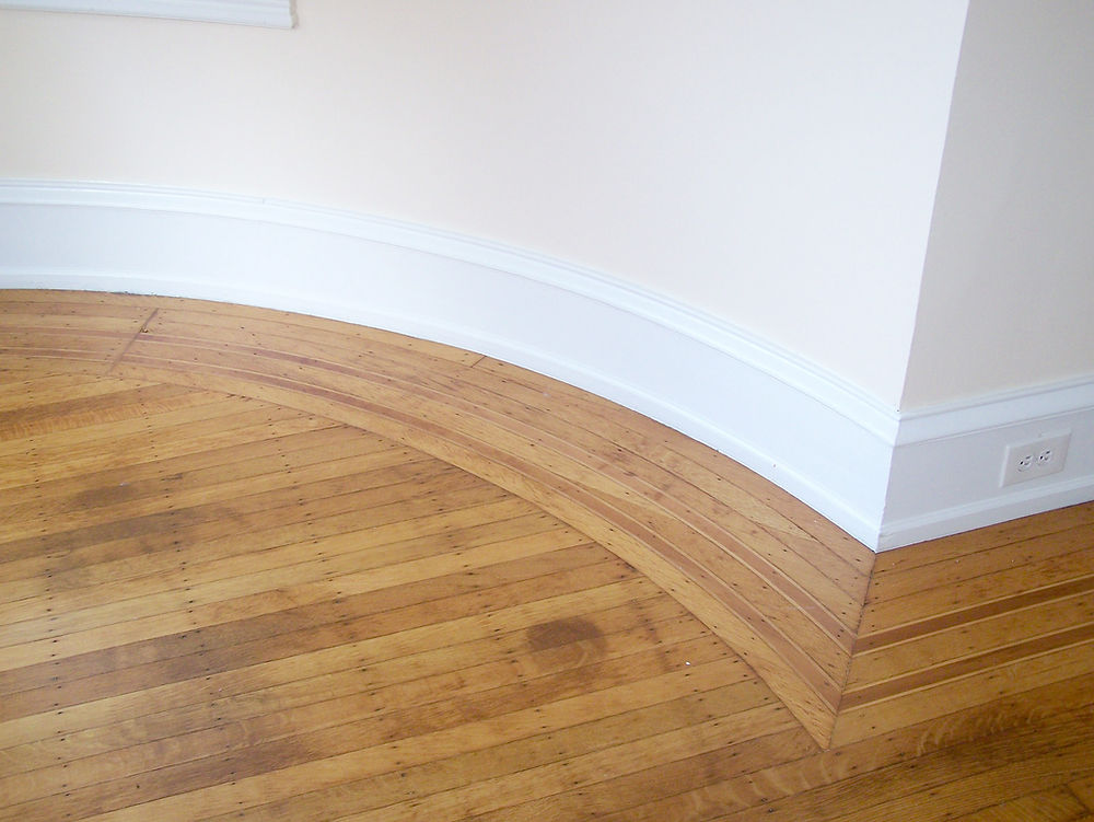 Curved hardwood floor, white baseboard, Rhode Island carpentry